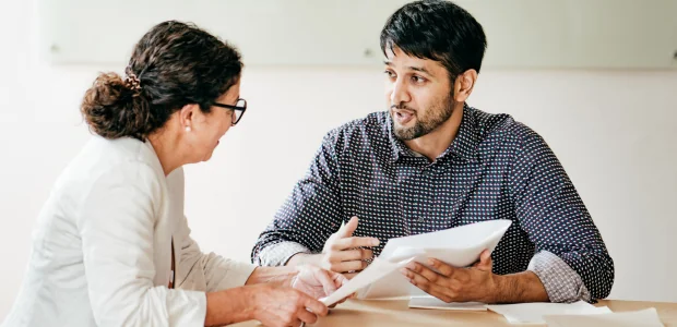 Symbolbild: Zwei Personen diskutieren Bewerbungsunterlagen