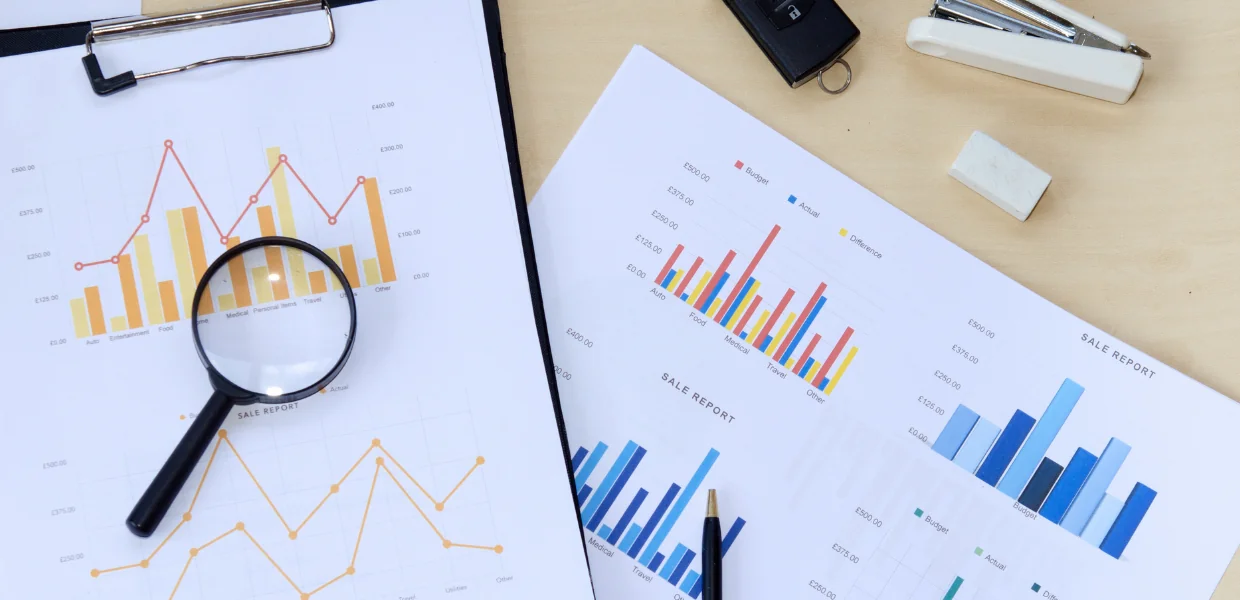 Symbolbild Controlling: Sales Report und Lupe liegen auf einem Tisch